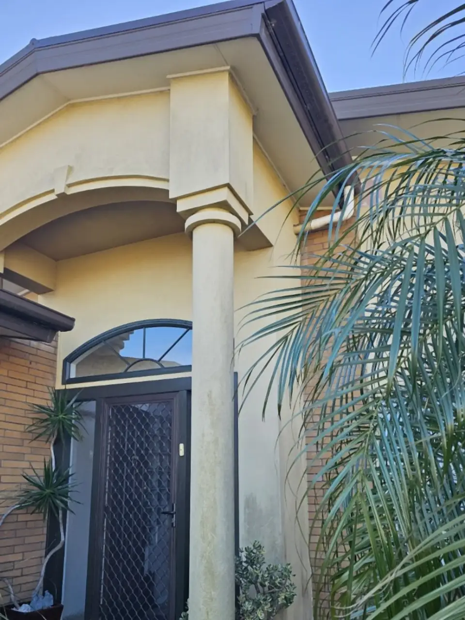 Before: An arched front entrance with columns, the plaster dark with grime