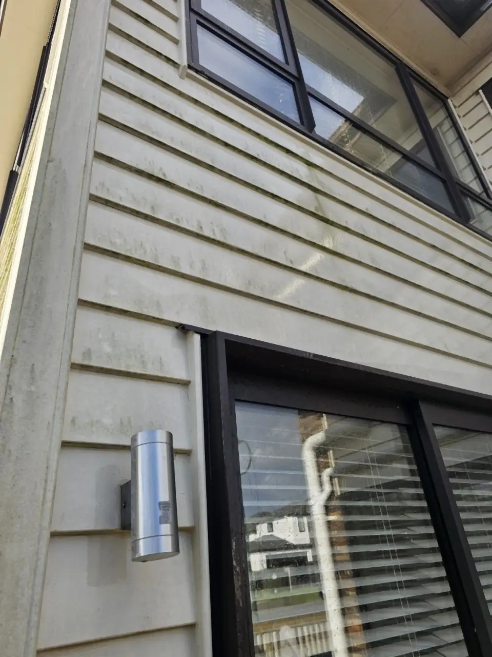 Before: Cream weatherboards streaked with green mould and dirt above a sliding door