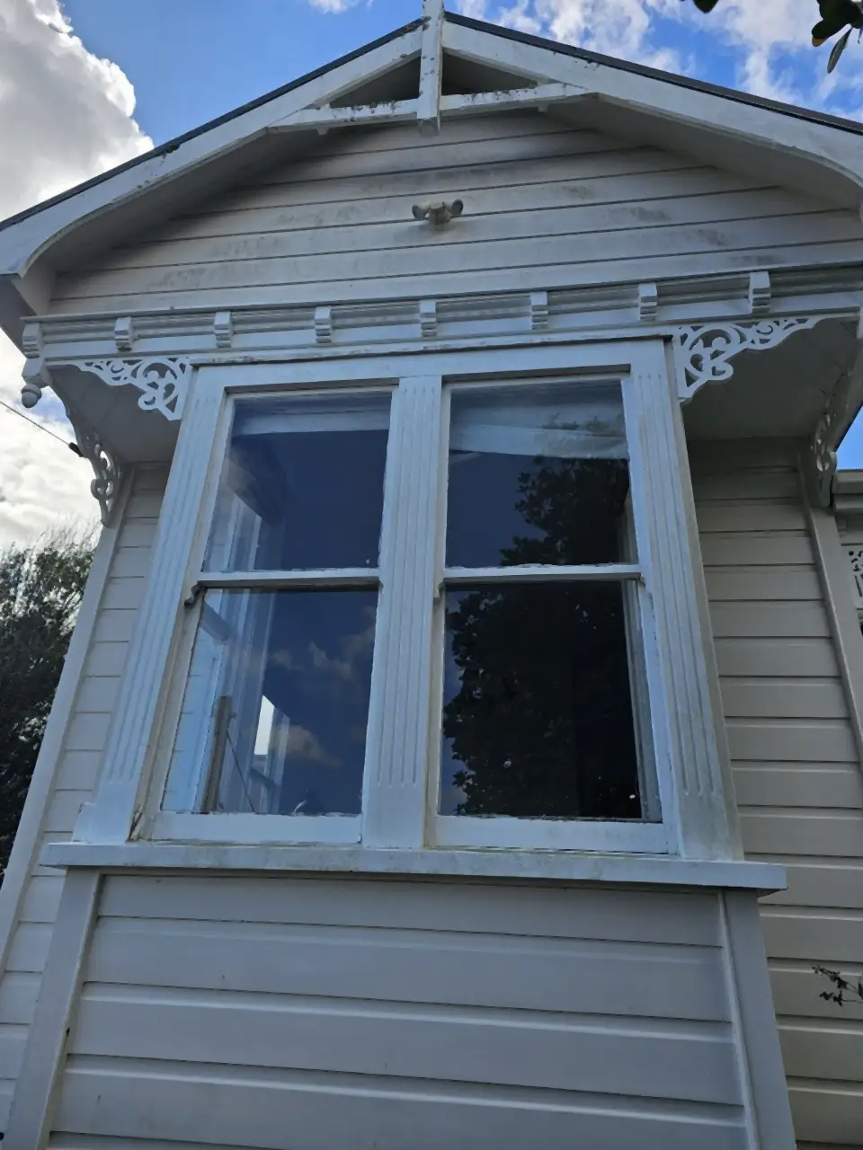 Before: A villa's bay window and gable, dull and grimy