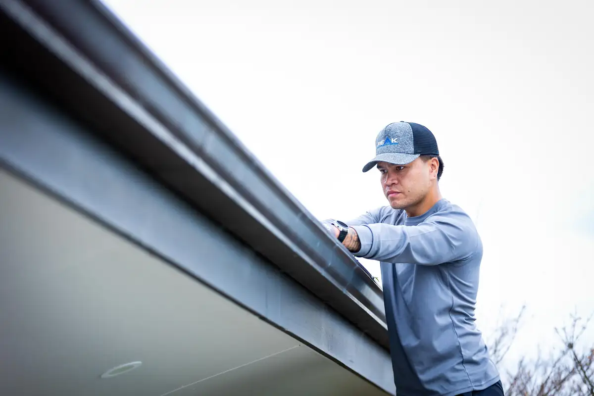 Logan working along a gutter at the edge of a roof